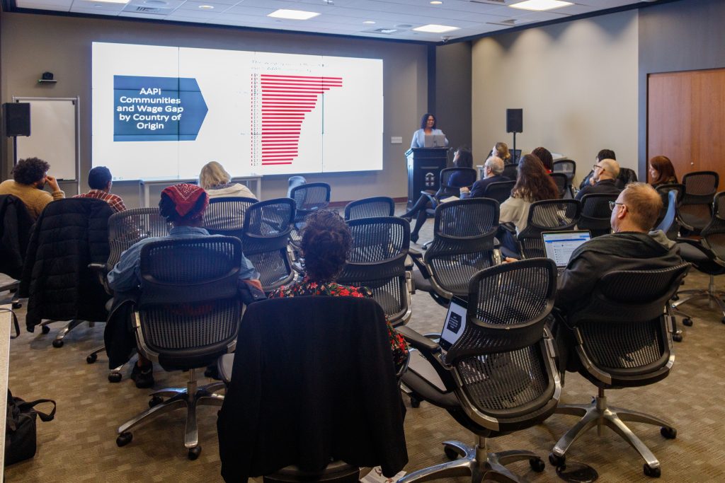 group of people sitting in desk chairs attending a presentation on AAPI communities and wage gap by country of origin in CDS