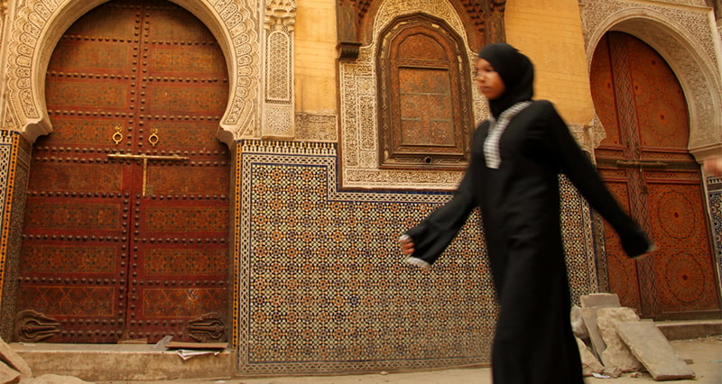 Muslim woman walking by a mosque