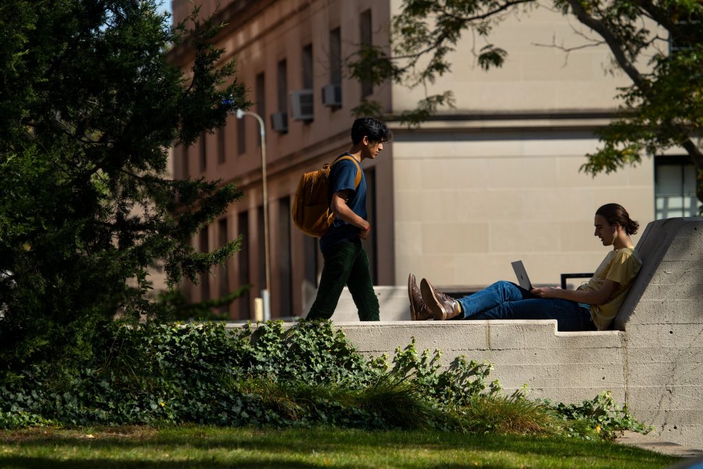 A student studies on a wall outside of the Sciences Library SciLi in the fall weather.