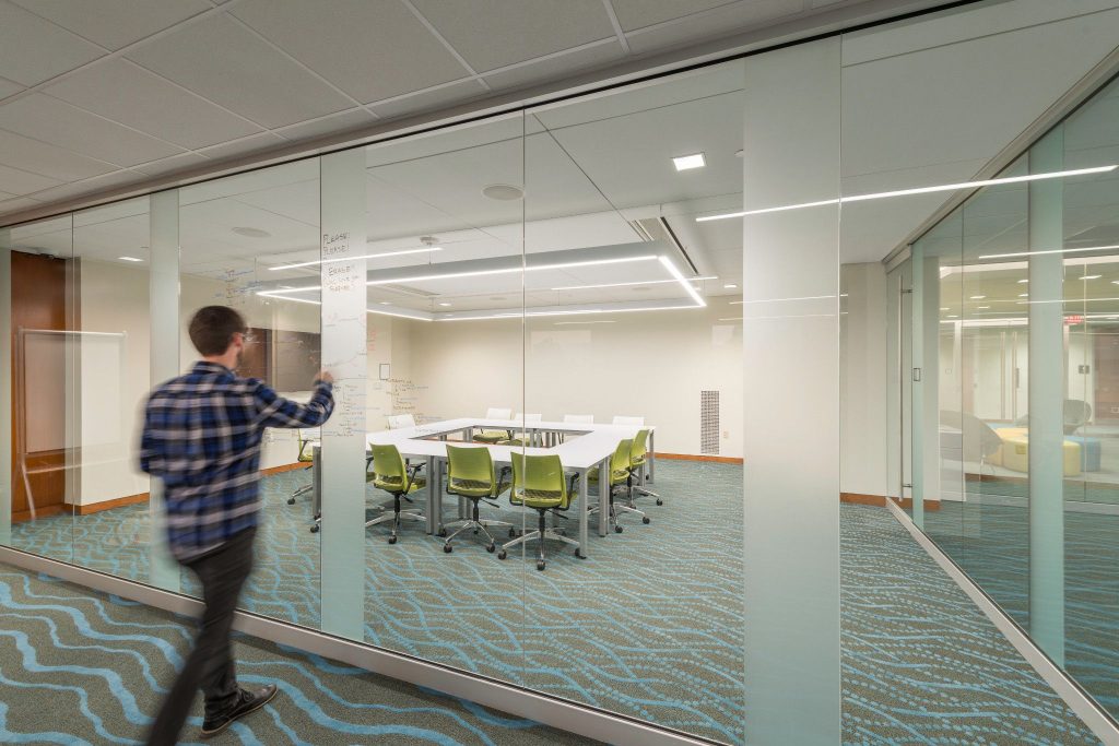 Student pushing door to enter glass walled conference room in grad study center