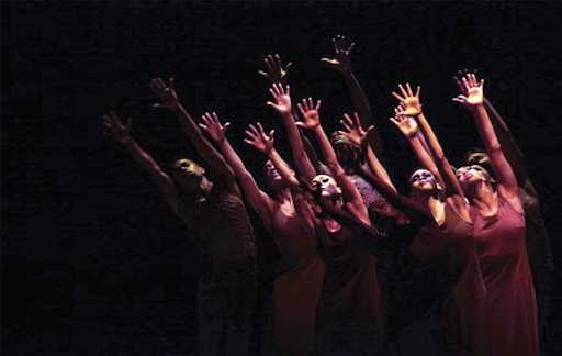 group of dancers with arms raised, hands open