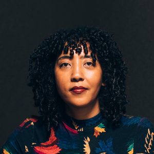 photo of woman's head and shoulders in floral shirt on a black background