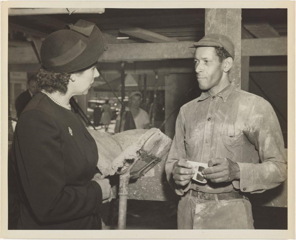 black and white photo of Martha Sharp on campaign trail conversing with man in workman's clothes
