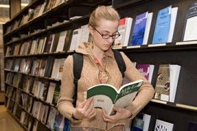 Photograph of student reading a journal in the Library stacks