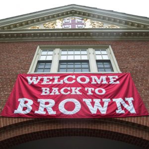 flag beneath a window at Brown University that reads, "Welcome back to Brown."
