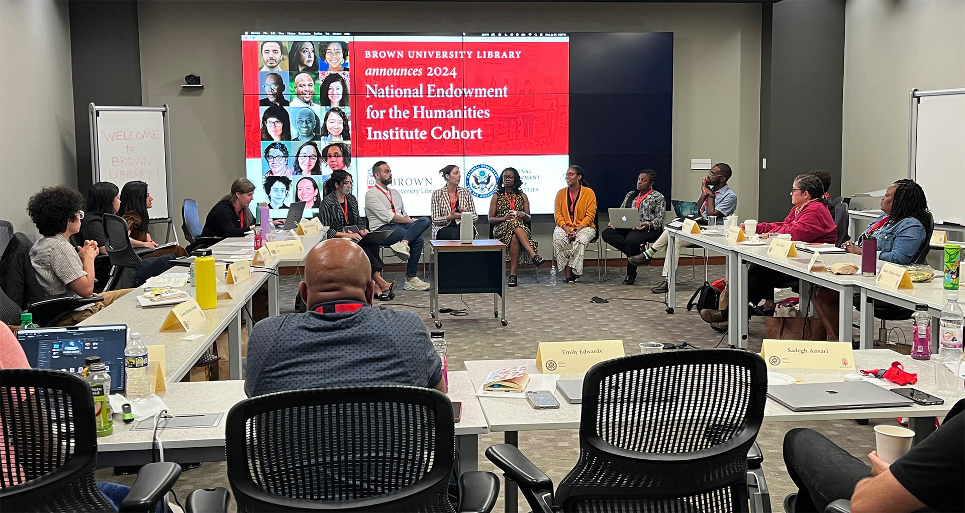 2024 cohort of Born-Digital Scholarly Publishing: Resources and Roadmaps. Cohort members are seated at tables and attending a presentation, which takes place in the background.